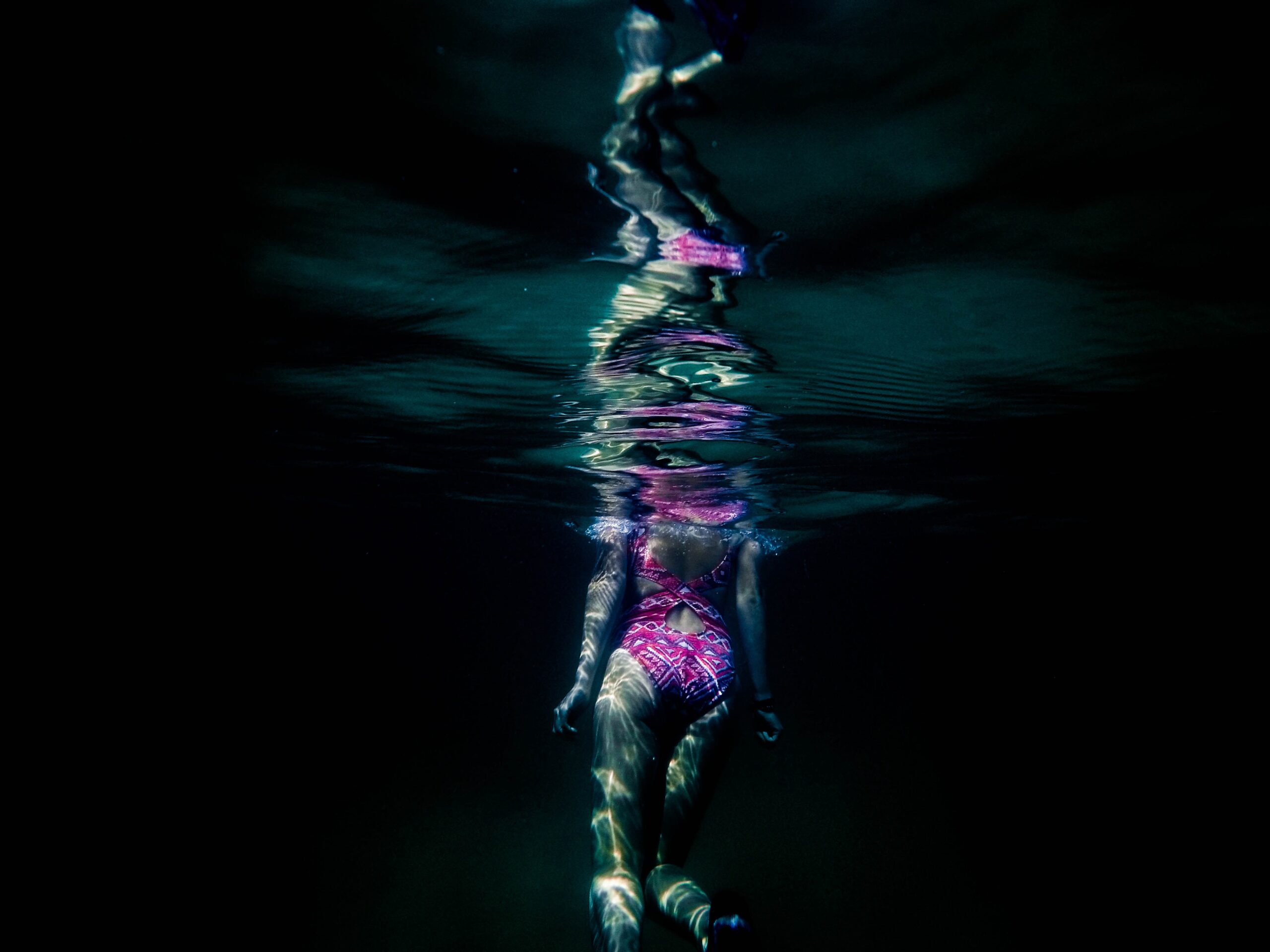 vrouw zwemt van donker water omhoog naar licht